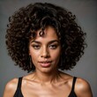 © Besler - A young Black woman with a medium-dark complexion, wearing a black sleeveless top. She has voluminous, curly black hair styled in a large afro, with loose curls framing her face.