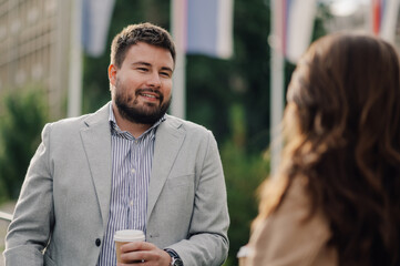 Wall Mural - Businessman holding coffee having pleasant conversation with female colleague