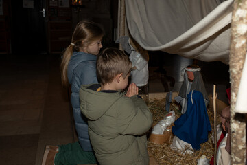 Wall Mural - A child praying near a Christmas nativity scene with baby Jesus Creche Figurines