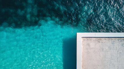 Poster - A top view of the edge of an outdoor swimming pool, focusing on its shimmering turquoise water and white edges