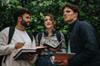 © qunica.com - A group of students engaging in a lively discussion outdoors, surrounded by greenery. They are holding books, suggesting a focus on study and collaboration.