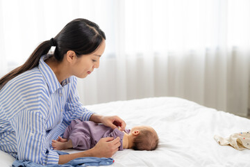 Canvas Print - Asian mom take care of her baby son with change of clothes at home