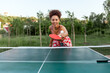 © Богдан Маліцький - young african american girl playing table tennis outdoors in the park, woman hitting the ball with a ping pong racket