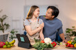 © Wasana - A man and woman are eating vegetables together in a kitchen