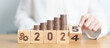 © Jo Panuwat D - 2024 end year to Happy New Year 2025 with Coins stack and gear icon. business Process, Team, teamwork, Strategy, goal, Money, Budget, investment, financial and New Year Resolution concept