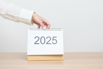 Poster - Business woman hand change 2025 Year Calendar on table in office background. countdown, Happy New Year, Resolution, Year End and New Start and Goals Plan Action Concept