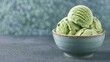 © artchvit - Organic matcha dessert. A bowl of creamy green ice cream scoops, showcasing a smooth texture against a soft, textured background.