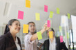© SOMKID - Asian businesswoman teamwork planning with sticky notes and new ideas on a glass wall, Business people brainstorming strategy and new ideas concept, startup worker meeting,
