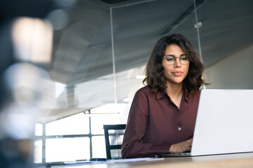 focused young professional it specialist latin hispanic business working on laptop pc sitting at des
