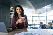 © Stock 4 You - Young Indian business woman manager ceo using cell phone mobile app. Portrait at camera Latin Hispanic female businesswoman holding smartphone in office trading, reading, working online. Copy space