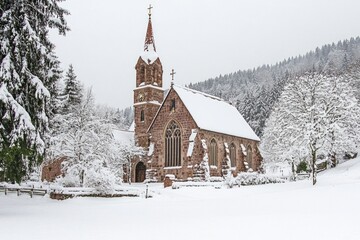 Aufkleber - A picturesque scene featuring a small church situated in the midst of a snow-covered forest
