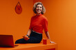 © Jacob Lund - Happy mature woman smiling in a vibrant monochromatic orange office setting, conceptual studio portrait