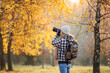 © encierro - Woman hipster with camera taking picture of autumn leaf. Tourist hiking in birch forest. Landscape photographer with backpack enjoying nature in fall season