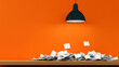 © PTC_KICKCAT - A modern workspace featuring a lamp above a heap of scattered papers on a wooden table, set against a vibrant orange wall.