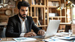 © Graphic Master - Professional Arabian man in a suit focused on his laptop screen.