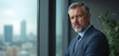 © Yury - Serious businessman with contemplative expression looking out office window against city skyline