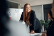 © Flamingo Images - Young businesswoman laughing while giving a presentation to coworkers in an office