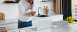 © Dmytro Hai - Web banner of african american man talking on smartphone and holding book near laptop in kitchen
