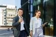 © muse studio - Business Professionals Walking Outside Modern Office Building While Using Mobile Devices in the Daytime