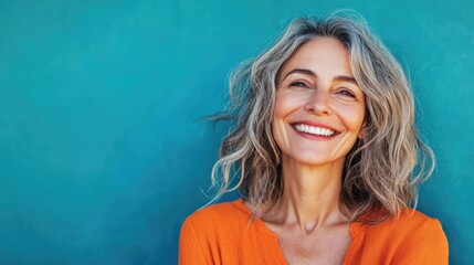 cheerful beautiful mature woman with a vibrant smile standing against a blue background .close up po