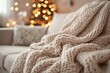 © Tacker - Cozy knitted blanket on couch with festive lights background