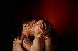 © Connect Images - An intimate moment between a couple as they embrace and kiss, illuminated by soft, warm light against a dark backdrop.