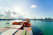 © Connect Images - Cargo ship loaded with colorful containers heads out to sea on a clear day with a busy port in the background, Singapore