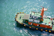 © Connect Images - Aerial view of an orange and green tugboat on crystal blue waters, Singapore