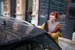 © Connect Images - Smiling woman with red hair looking away standing by a car on a city street, Brussels, Belgium