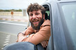 © Connect Images - Smiling bearded man leaning out of a car window, exuding a cheerful and relaxed vibe.