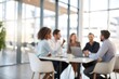 © NRdS - A softly blurred scene of business people gathered around a table in a modern office.