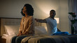 © Yuliia - Sad offended African American woman wife feeling bad about breakup problem relationship trouble with erectile dysfunction man husband touch female calming lady walk away couple family on bed at night