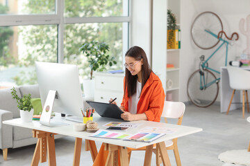 Poster - Young female graphic designer working with tablet at table in office