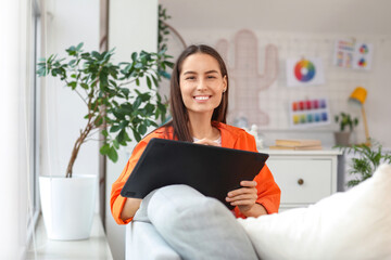 Poster - Young female graphic designer working with tablet on sofa in office