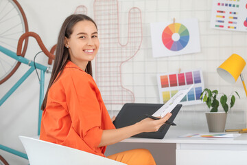 Poster - Young female graphic designer working with tablet at table in office