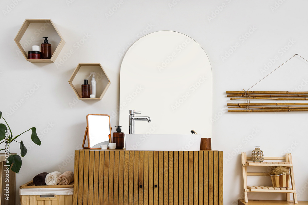 Modern sink, mirror and bath supplies on cabinet in bathroom