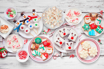 Poster - Cute Christmas desserts table scene. Overhead view on a white wood background. Fun holiday baking concept. Cookies, brownies, donuts, cupcakes and sweets.