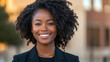 © Vertigo Images - A young Black woman smiles warmly with her hair in a curly afro style.