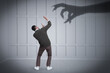 © New Africa - Man scared by monstrous hand reaching for him. Creepy shadow on light wall