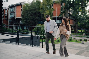 Business people walking down stairs holding coffee and talking