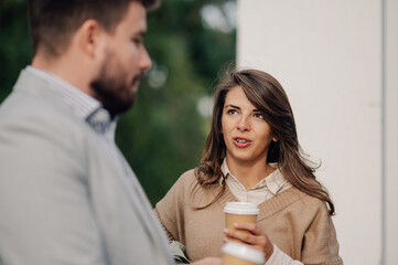 Wall Mural - Businesswoman holding coffee cup talking to businessman outdoors