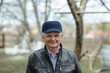 © sharshonm - One modern senior caucasian man portrait of male grandfather without a beard and hat cap stand in front of his house in day wear shirt happy confident copy space.