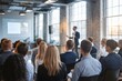 © StreamPixel - group of people attending a presentation in a modern, well-lit room with large windows and exposed brick walls.