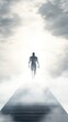 © isti - A figure walks towards a bright light on a foggy path, symbolizing hope or transcendence.