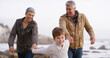 © peopleimages.com - Grandparents, grandchild and walking on beach, outdoor and seashore for bonding together. Senior people, boy and weekend for holding hands, care and vacation on winter holiday with family for support