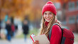 © UniqGraphicX - Young smiling college girl at college campus holding books and notebooks.