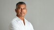 © Robert Kneschke - Confident Hispanic man in his 50s with a poised expression, short gray hair, and a white shirt against a neutral background