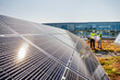 © Westend61 - Two technicians studying plan on the roof of a company building with solar panels