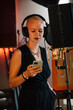© Westend61 - Singer wearing headphones and using smart phone in recording studio