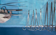 © Westend61 - Hand of nurse holding surgical tool near scissors over operating table